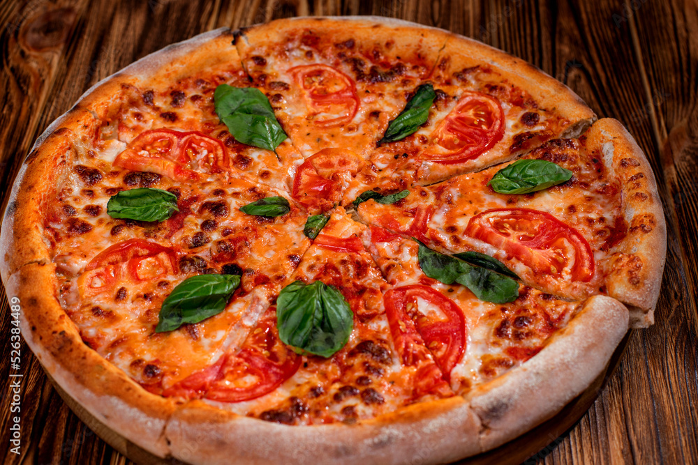 Delicious fragrant pizza-Margherita with mozzarella, tomatoes and basil on tomato sauce on woden background. Copy space