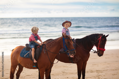 Kids riding horse on beach. Children ride horses. © famveldman