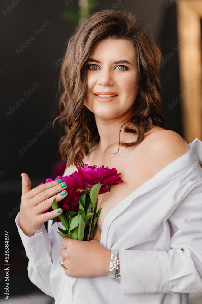 A gentle brunette woman in white clothes with a bouquet of peonies. A gentle brunette woman in white clothes with a bouquet of peonies.