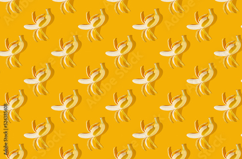 Pattern of peeled bananas on orange pastel background