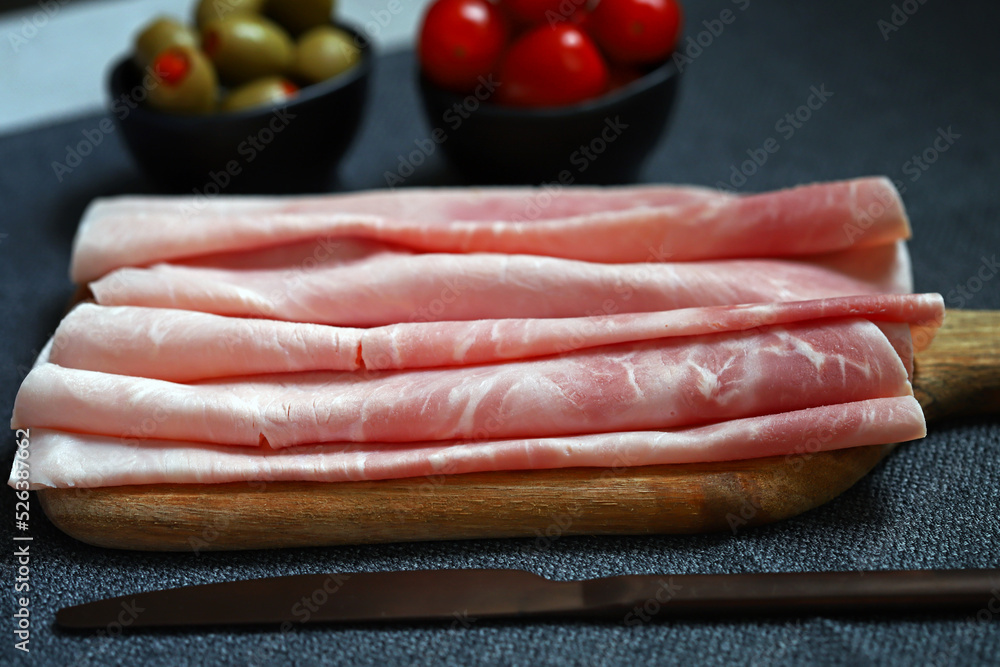 Prosciutto cotto on a wooden board with olives and cherry tomatoes. Italian appetizer. Prosciutto cotto on a wooden board with olives and cherry tomatoes. Italian appetizer.