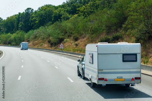 Motorhomes driving along a lonely highway lined with trees.