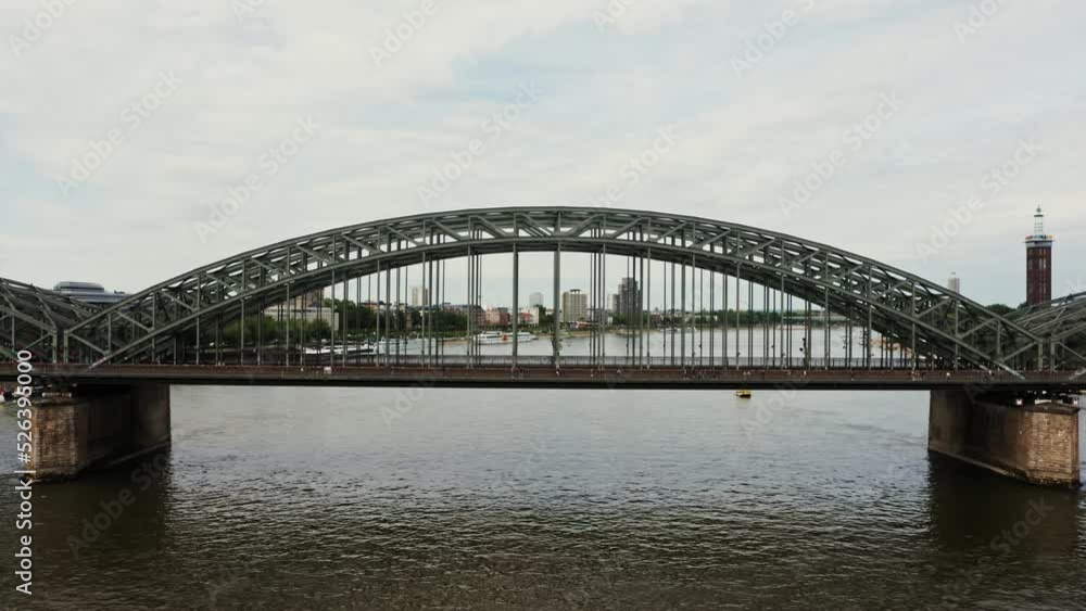 Drone video, view of the railway-pedestrian bridge in the city of Cologne. A bridge with metal semicircles rising above the road, aerial view from the river. Drone video, view of the railway-pedestrian bridge in the city of Cologne. A bridge with metal semicircles rising above the road, aerial view from the river.