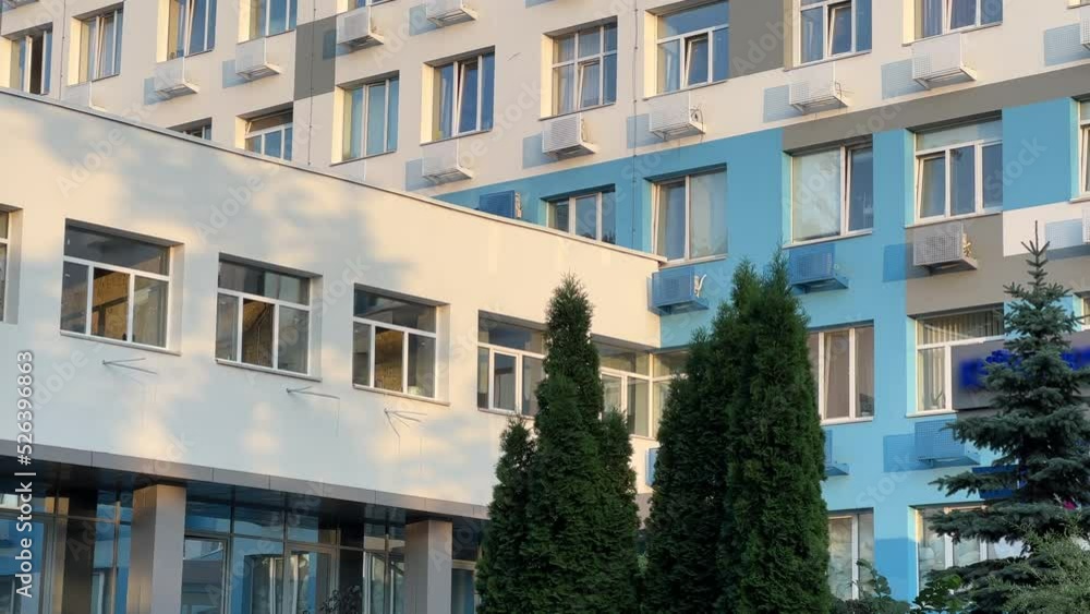 Hospital exterior with transition between buildings. Medium angle view of clinic windows.
