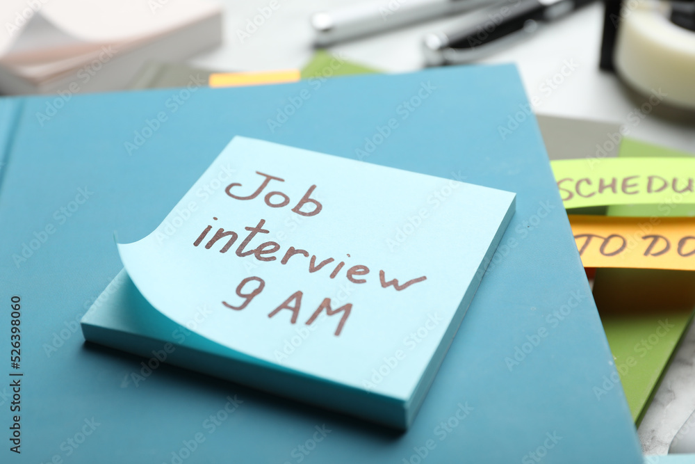 Reminder note about job interview and stationery on table, closeup Reminder note about job interview and stationery on table, closeup