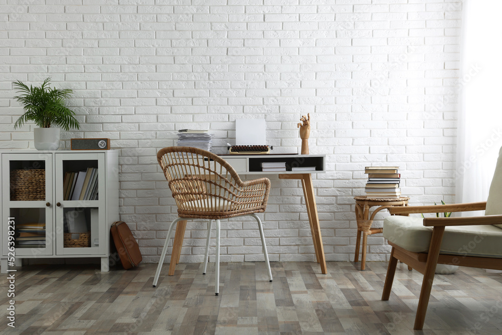 Fototapeta premium Comfortable writer's workplace interior with typewriter on desk near white brick wall