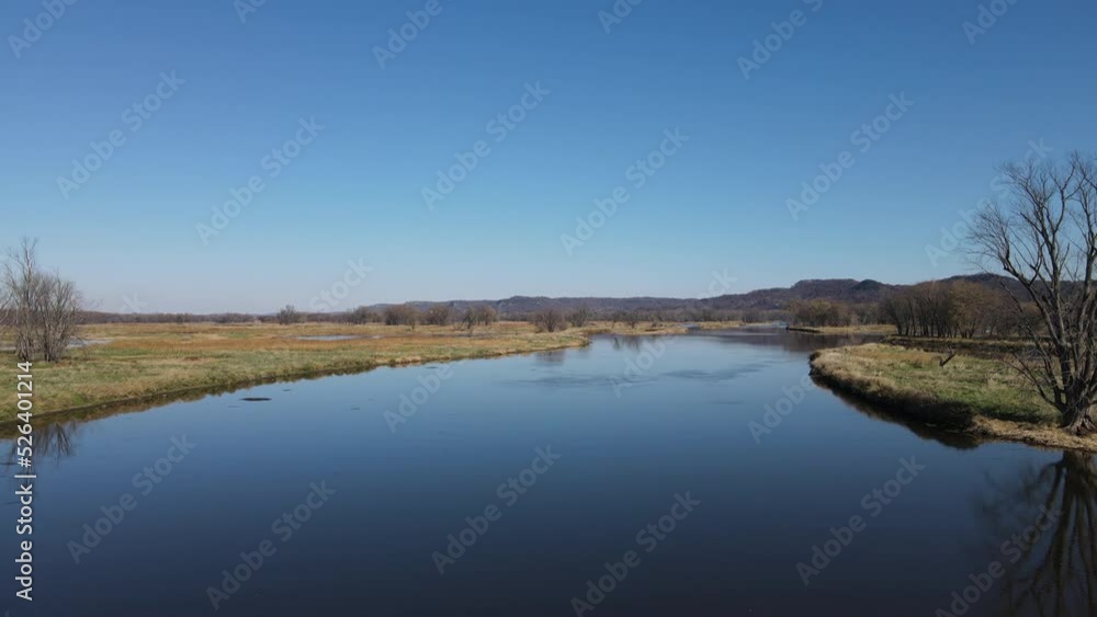 Wide landscape view of waterways in Wisconsin in autumn. Calm glistening water. Reflections from the sun on the water. Bare trees dotting the island. Patches of green grass Wide landscape view of waterways in Wisconsin in autumn. Calm glistening water. Reflections from the sun on the water. Bare trees dotting the island. Patches of green grass