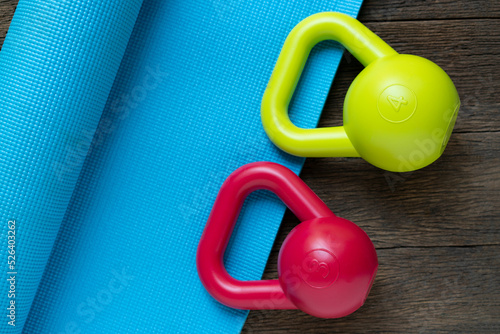 colorful kettlebell and blue yoga mat on wooden table, fitness healthy and sport concept
