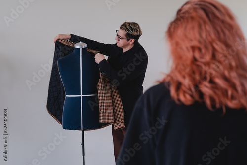 Tailor showing a suit to a female client. Tailor selling a suit. Fashion designer arranging a suit on a mannequin. High quality photo