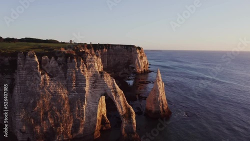 Beautiful coastal cliffs of bizarre shapes with natural arches and wild beaches in the rays of the setting sun. Etretat, France, cliffs on the banks of the English Channel, drone video