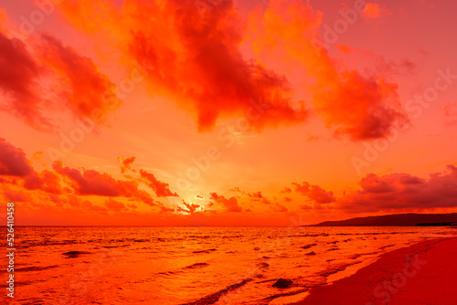Vibrant sunrise, scattered clouds painted in orange and pink tones, ocean waves.