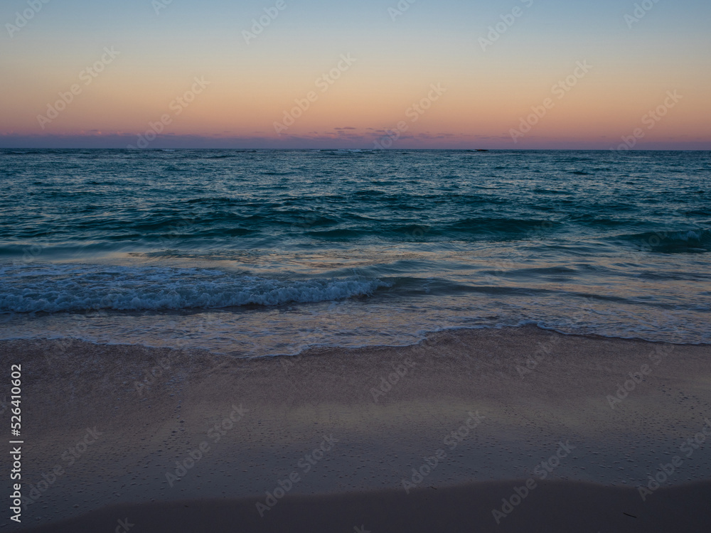 Sunset on the ocean. A beautiful beach with white sand, a turquoise wave runs onto the shore. Relaxing landscape without people