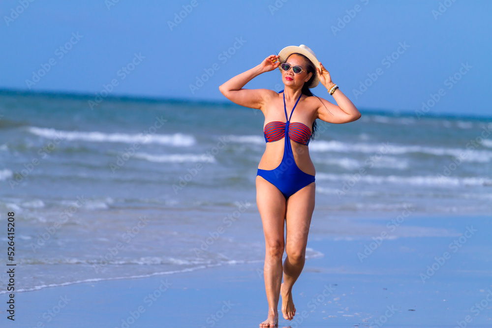 Woman happy walk with swimsuit and hat at beach