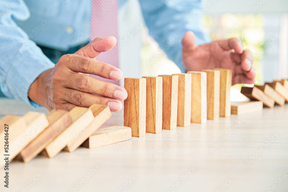 Close-up hand prevent wooden block not falling domino concepts of financial risk management and strategic planning and business challenge plan. Close-up hand prevent wooden block not falling domino concepts of financial risk management and strategic planning and business challenge plan.