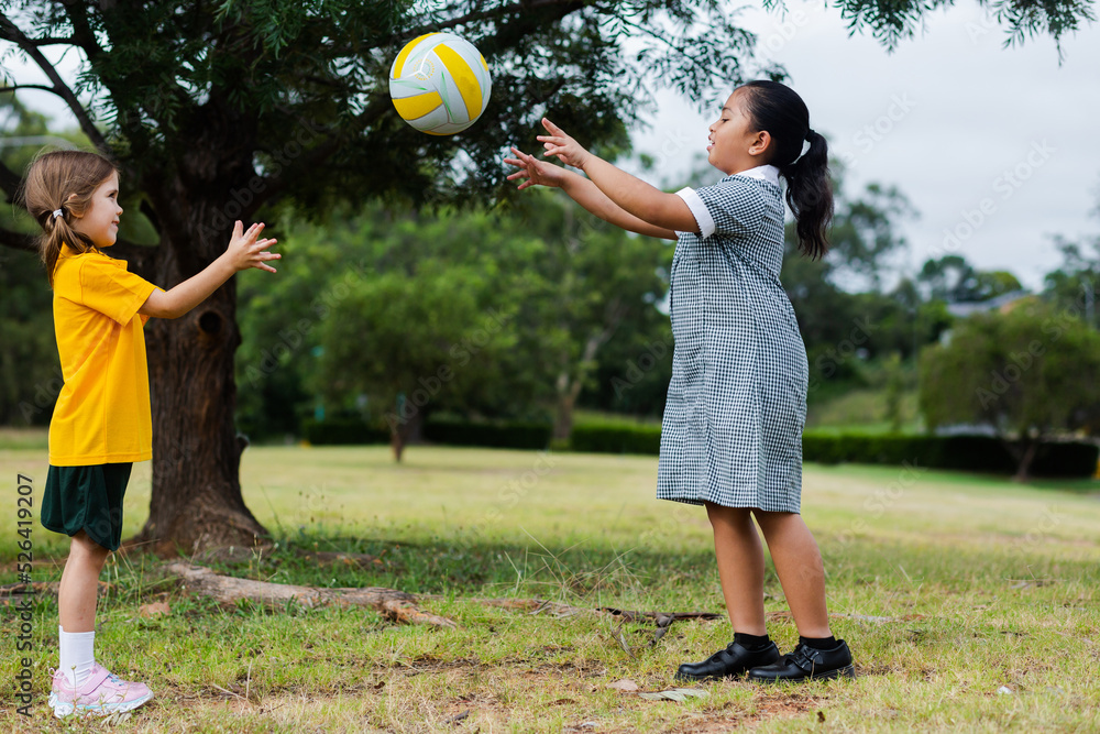 Two girls playing outside at school throwing and catching a ball foto