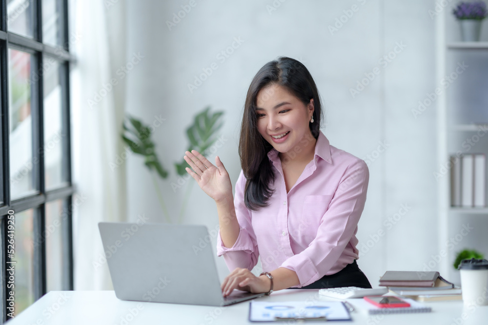 Asian businesswoman having a video call meeting on her laptop in the office comfortably and cheerfully. Asian businesswoman having a video call meeting on her laptop in the office comfortably and cheerfully.