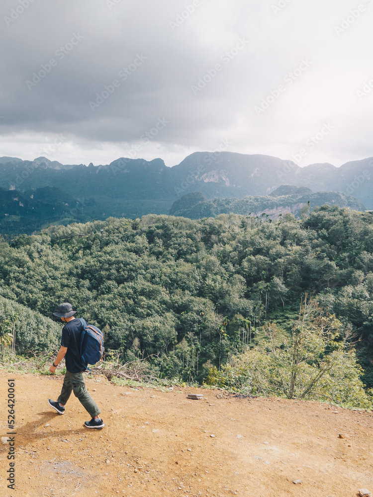Hiking man with backpack walking in the mountains on sunny day and taking in the beautiful mountain views. Hiking man with backpack walking in the mountains on sunny day and taking in the beautiful mountain views.