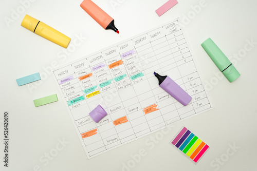 School schedule. A sheet with a handwritten school schedule lies on a white table strewn with colorful markers and stickers. School Time Management