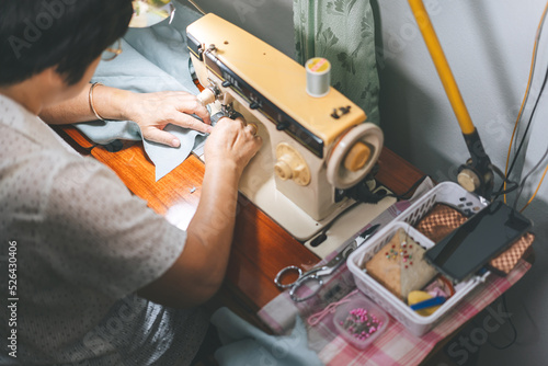 Retriement tailor southeast asian elderly crafting a cloth by sewing machine working at home photo