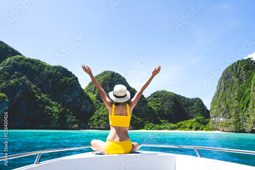 Rear view of young adult traveling tourist woman hand raised sitting on the sailing boat on summer vacation southeast asia trip