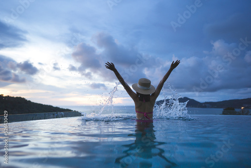 Rear view of woman hand raised happy relax at outdoor pool resort sea panorama sky view in southeast asia tropical © dodotone