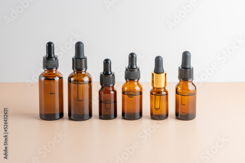 Set of famous dropper bottles with essential oils of beauty face serum with collagen, peptides, vitamins and extracts on a beige background.
