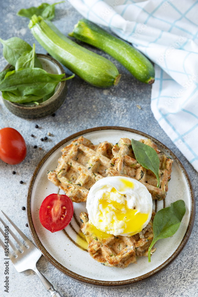 The concept of dietary and healthy breakfast. Spinach and zucchini vegan waffles with a poached egg on a stone tabletop. The concept of dietary and healthy breakfast. Spinach and zucchini vegan waffles with a poached egg on a stone tabletop.