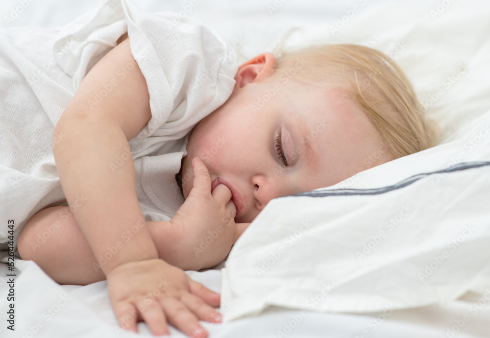 Little girl sleeping at home on the bed under the covers and sucking her thumb Little girl sleeping at home on the bed under the covers and sucking her thumb