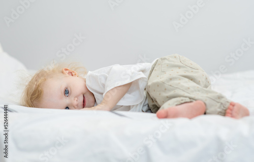 Little girl lying on the bed in the bedroom and with a cute smile