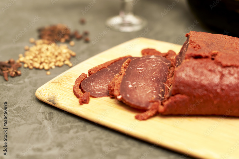 sliced basturma on a plate next to a bottle of wine and a glass