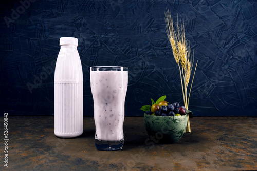 Yogurt in a glass and a plastic bottle. A variety of berries and spikelets of wheat. Yogort with berries and cereals.