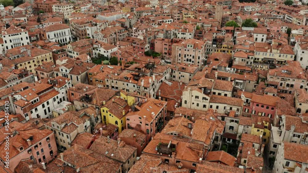 The drone flies over the orange rooftops of traditional Venetian houses. Narrow water channels instead of streets, aerial view, Italy The drone flies over the orange rooftops of traditional Venetian houses. Narrow water channels instead of streets, aerial view, Italy