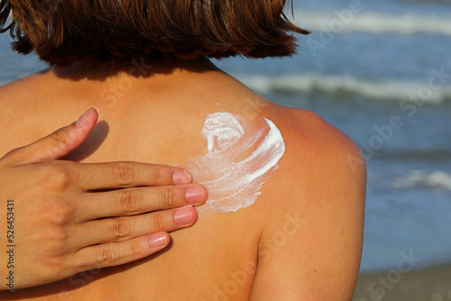 Bild auf Leinwand hand who affectionately smears sun cream on their back for sunburn protection