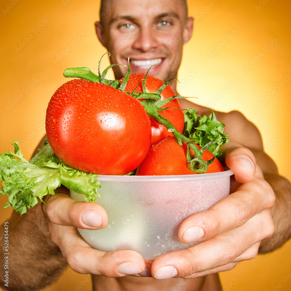 Diet and healthy lifestyle. A man with an athletic body holds ripe tomatoes. Diet and healthy lifestyle. A man with an athletic body holds ripe tomatoes.