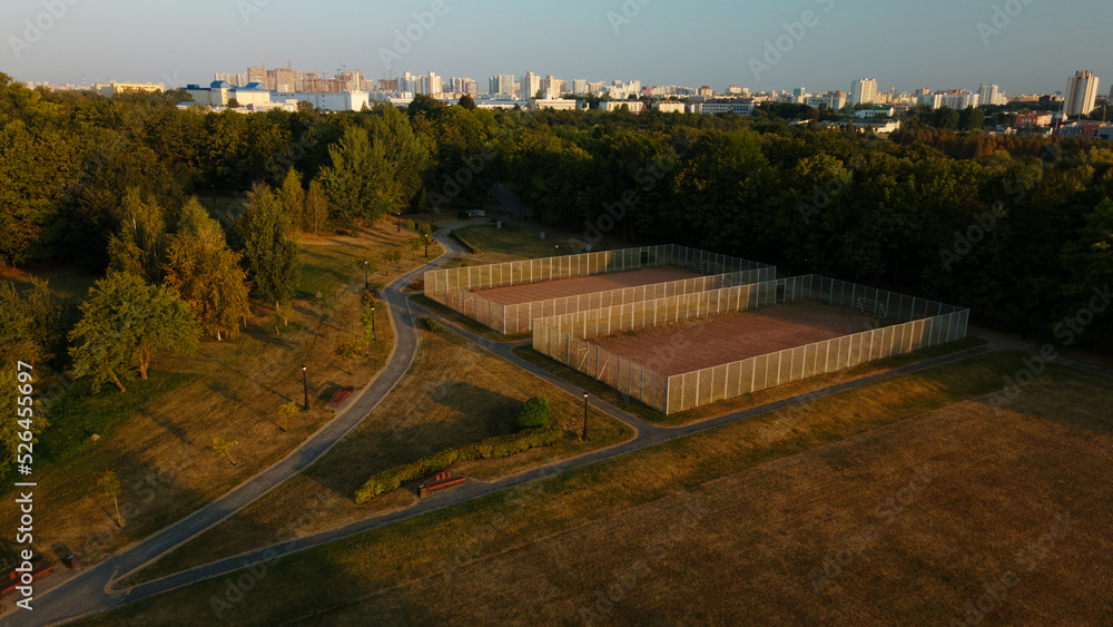 Ground sports grounds in the city park. With a mesh fence. City park at dawn. Aerial photography.