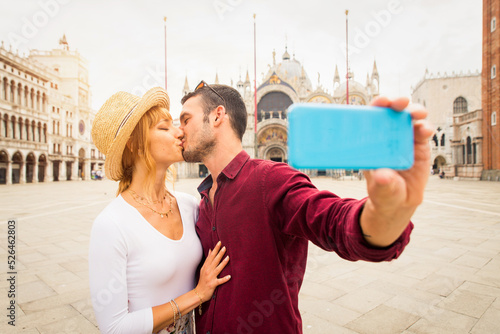 Happy beautiful couple of lovers doing romantic trip in Venice, Italy - Tourists visiting historic town of Venice and St. Mark square photo