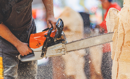 Close-up woodcutter sawing chain saw in motion, sawdust fly to sides. Concept Chainsaw industry