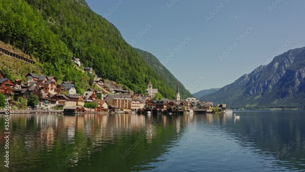 Beautiful view of a small village located in a lowland between green mountains on the lake. Panoramic drone footage from the water side, Hallstatt, Astria Beautiful view of a small village located in a lowland between green mountains on the lake. Panoramic drone footage from the water side, Hallstatt, Astria