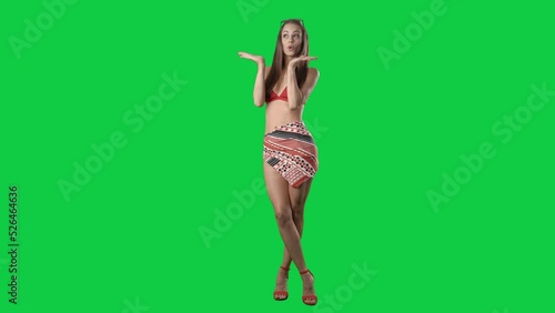 Happy sensual young woman in red bikini posing and modelling at camera. Full body isolated on green screen background