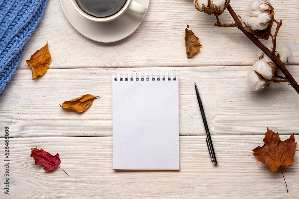 Cup of coffee, plaid, gratitude journal, autumn leaves on white wooden background.
