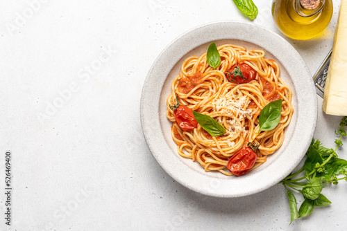 Spaghetti pasta with tomatoes and basil in ceramic plate on white background. Traditional Italian pasta with tomato sauce. Mediterranean cuisine