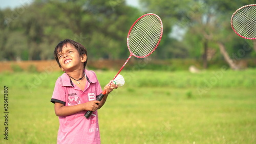 A boy plays tennis on a local ground. A little tennis player focused on the game and shot in flight after hitting the ball. Tennis kid. Sports action frame. Active games. Square size. © Govind