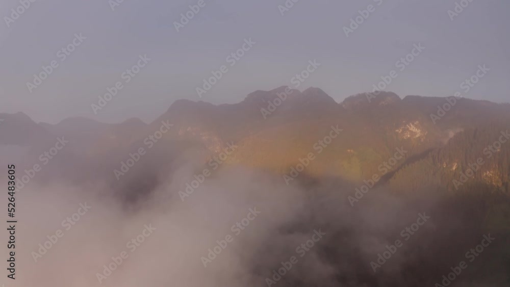 The drone flies out of the white cloudy veil, opening up a beautiful view of the mountain peaks flooded with sunlight. Alps, Austria The drone flies out of the white cloudy veil, opening up a beautiful view of the mountain peaks flooded with sunlight. Alps, Austria
