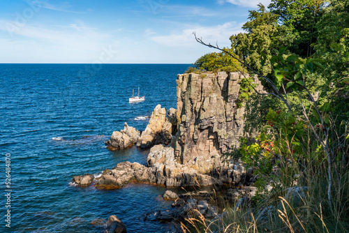 Boat passing by Sanctuary Cliffs of the northern coast of Bornholm island - Helligdomsklipperne (Sanctuary Rocks), Denmark photo