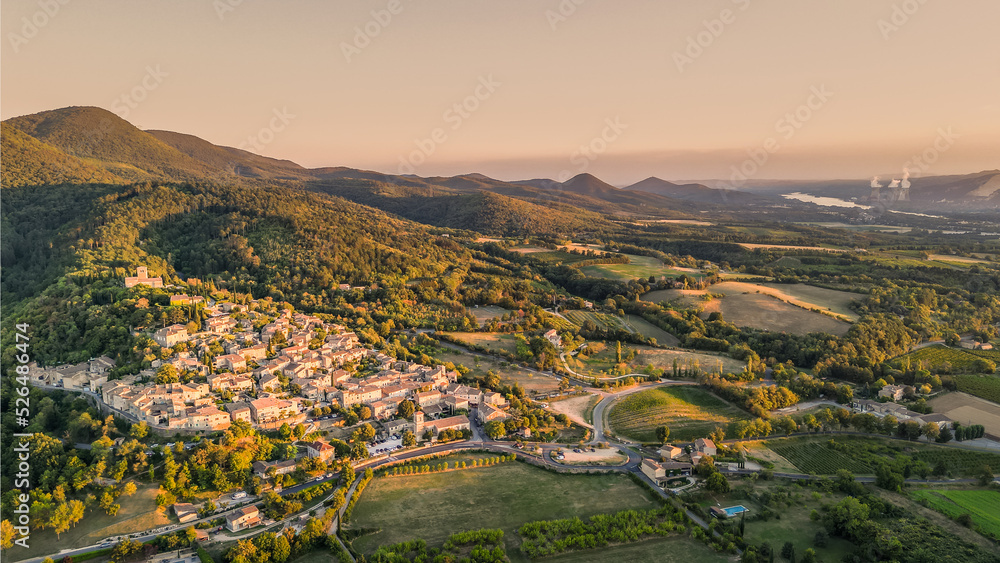 Panoramic drone view of one of the most beautiful French towns in southern France - Mirmande. Old historic town. Sunset over the surrounding mountains. Chimneys from the power plant in the distance