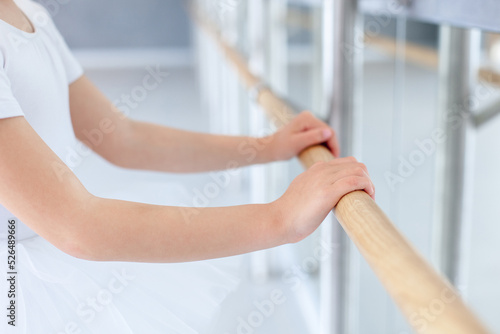 Hands on barre in ballet school. Little ballerina studying in classical dance class room. Child girl training in studio. Kid has dancing workout. Practicing for children, small dancer. Close up © Marina April