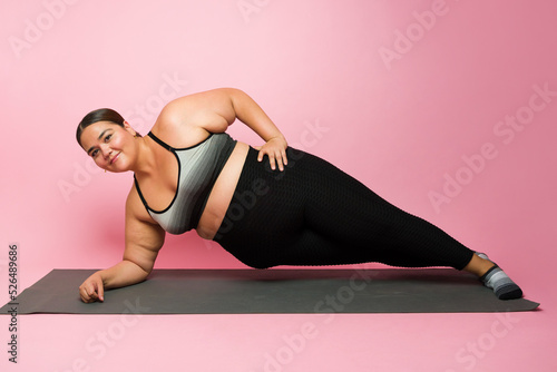 Canvas Print Full length of a beautiful fat woman practicing a side plank during a workout
