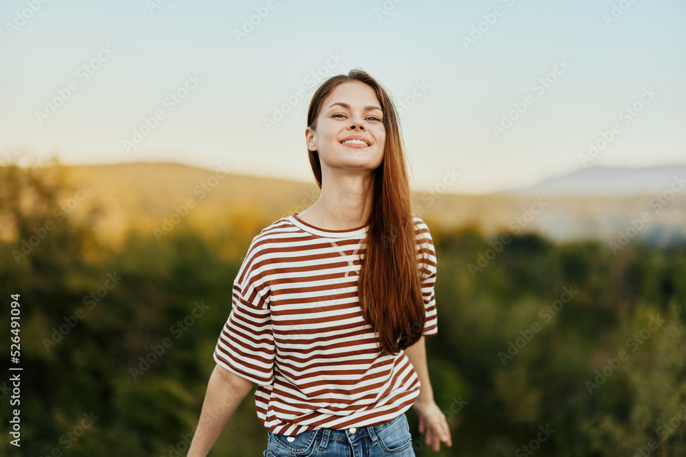 A woman smiles and pulls her hands to the camera close-up in nature with a view of the mountains. Happy travel lifestyle follow me