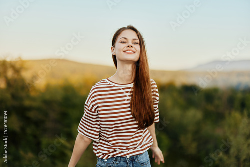 A woman smiles and pulls her hands to the camera close-up in nature with a view of the mountains. Happy travel lifestyle follow me