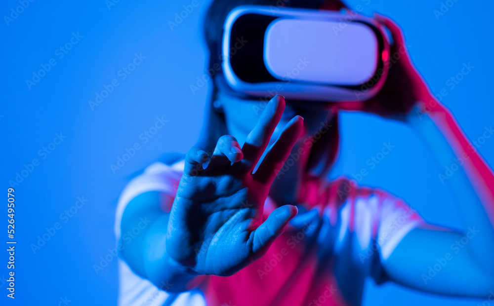 Attractive woman wearing virtual reality goggles. VR headset. Woman using finger to touch on imaginary panel viewing on VR device.